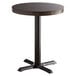 A Lancaster Table & Seating round table with a wood top and a black base plate.