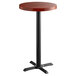 A Lancaster Table & Seating round wooden bar table with a black cast iron base.