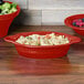 A Scarlet Fiesta oval casserole dish full of pasta and salad on a table.