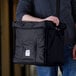 A man holding a black Cambro Insulated GoBag with a handle.