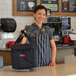 A woman holding a black Cambro Insulated Small Folding Delivery GoBag.
