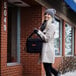 A woman in a white coat and hat holding a black Cambro Insulated GoBag.