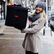 A woman holding a black Cambro delivery bag.