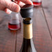 A hand using a Franmara Super Flex Seal Black Wine Stopper to close a bottle of wine.