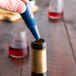 A hand using a Franmara dark blue Flex Seal wine stopper to open a bottle of wine.