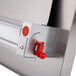 A stainless steel Estella thickness adjustment handle with a red button.