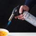 A hand holding a Sterno Butane fuel canister over a white bowl.