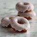 A group of donuts with confectioners icing sugar on them.