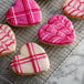 A heart shaped cookie with pink and white frosting.