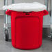A red Rubbermaid commercial trash can with a lid on it.