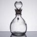 A close-up of a Libbey clear glass cruet with a metal stopper.