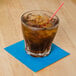 A glass with a straw and brown liquid with a blue Hoffmaster beverage napkin.