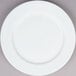 A Tuxton Alaska bright white china plate with a wide rim on a gray surface.