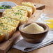 Sliced bread with garlic and herbs on a cutting board with a bowl of Regal granulated garlic.