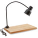 An Avantco black heat lamp on a wooden cutting board over a drip pan.