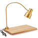An Avantco gold heat lamp on a wood cutting board.