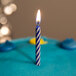 A blue cake with blue spiral candles on it.