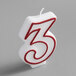 A white candle with a red outlined number three.