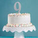 A white cake with a silver number nine on top.