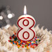 A white birthday cake with a red outlined number 8 candle.