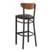 A Lancaster Table & Seating Boomerang bar stool with a dark brown vinyl seat and an antique walnut back.