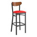A black Lancaster Table & Seating bar stool with red vinyl seat and wood back.