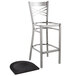 A Lancaster Table & Seating black metal cross back bar stool with a black wood seat pad.
