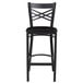 A Lancaster Table & Seating black metal bar stool with a black wood seat and cross back.