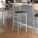Lancaster Table & Seating bar stools with dark brown vinyl seats and driftwood backs on a table in a pub interior.