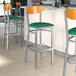A row of Lancaster Table & Seating bar stools with green vinyl seats and cherry wood backs.