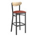 A Lancaster Table & Seating black bar stool with a wooden back and a red cushion.