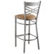A Lancaster Table & Seating metal cross back bar stool with a light brown cushion.