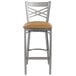 A Lancaster Table & Seating metal cross back bar stool with a light brown vinyl padded seat.