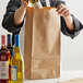 A person opening a Duro brown paper bag with a bottle of wine.