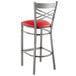 A Lancaster Table & Seating clear coat finish metal cross back bar stool with red vinyl padded seat.