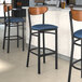 Three Lancaster Table & Seating Boomerang Series bar stools with blue vinyl seats and antique walnut backs.
