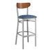 A Lancaster Table & Seating bar stool with a navy vinyl seat and walnut back.
