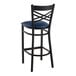 A Lancaster Table & Seating black cross back bar stool with navy blue padded seat.