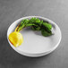 A white Elite Global Solutions Santorini melamine bowl with a yellow vegetable in it.