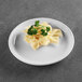 A close up of Elite Global Solutions white melamine plate with pasta and parsley.