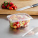 A Dart ClearPac 32 oz. plastic container with fruit and a flat lid on a counter.
