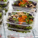 A group of Dart clear plastic containers of salad on a counter.