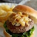 A burger with Savor Imports caramelized onions and cheese on a plate.