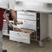 A man using a ServIt freestanding drawer warmer to prepare food in a kitchen.