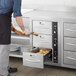 A man opening a ServIt narrow built-in drawer warmer filled with food.