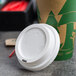A white plastic lid on a white paper cup filled with coffee.