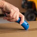 A hand using a Pacific Handy Cutter RSC-432 blue safety cutter to cut a box.