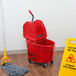 A Rubbermaid red mop bucket with a down press wringer and a dirty water bucket.