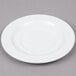 An Arcoroc white porcelain saucer with a small rim on a gray surface.