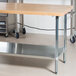 An Advance Tabco wood top work table with a galvanized metal shelf.